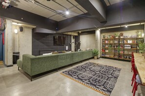 A modern lounge area with a green sofa, a patterned rug, a bookshelf, and a fireplace. - Modern-style Student Studio in London (London)