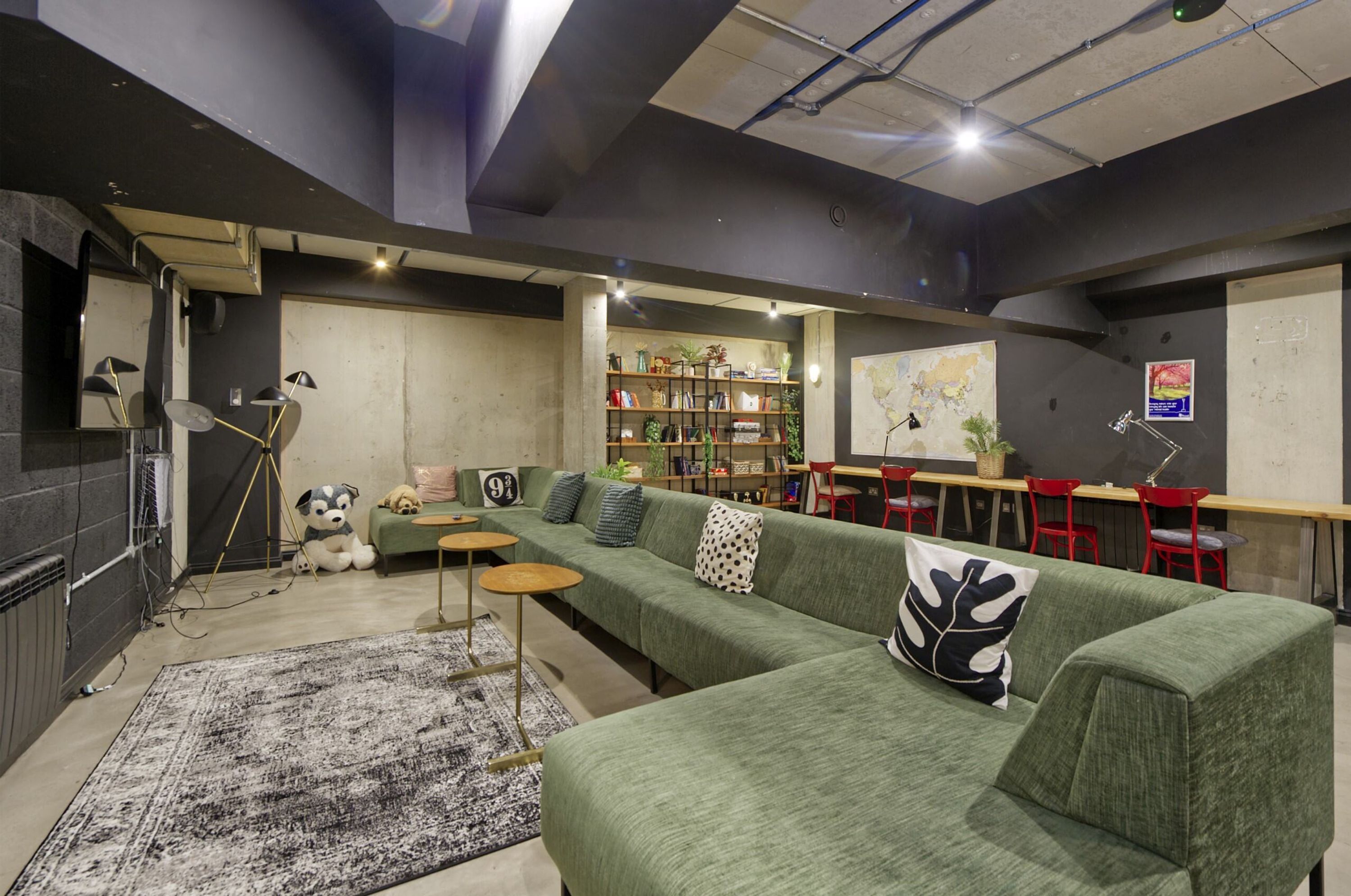 Ein modernes Wohnzimmer mit einem grünen Sofa, einem Couchtisch und einer Bücherwand voller Bücher und Dekoration.