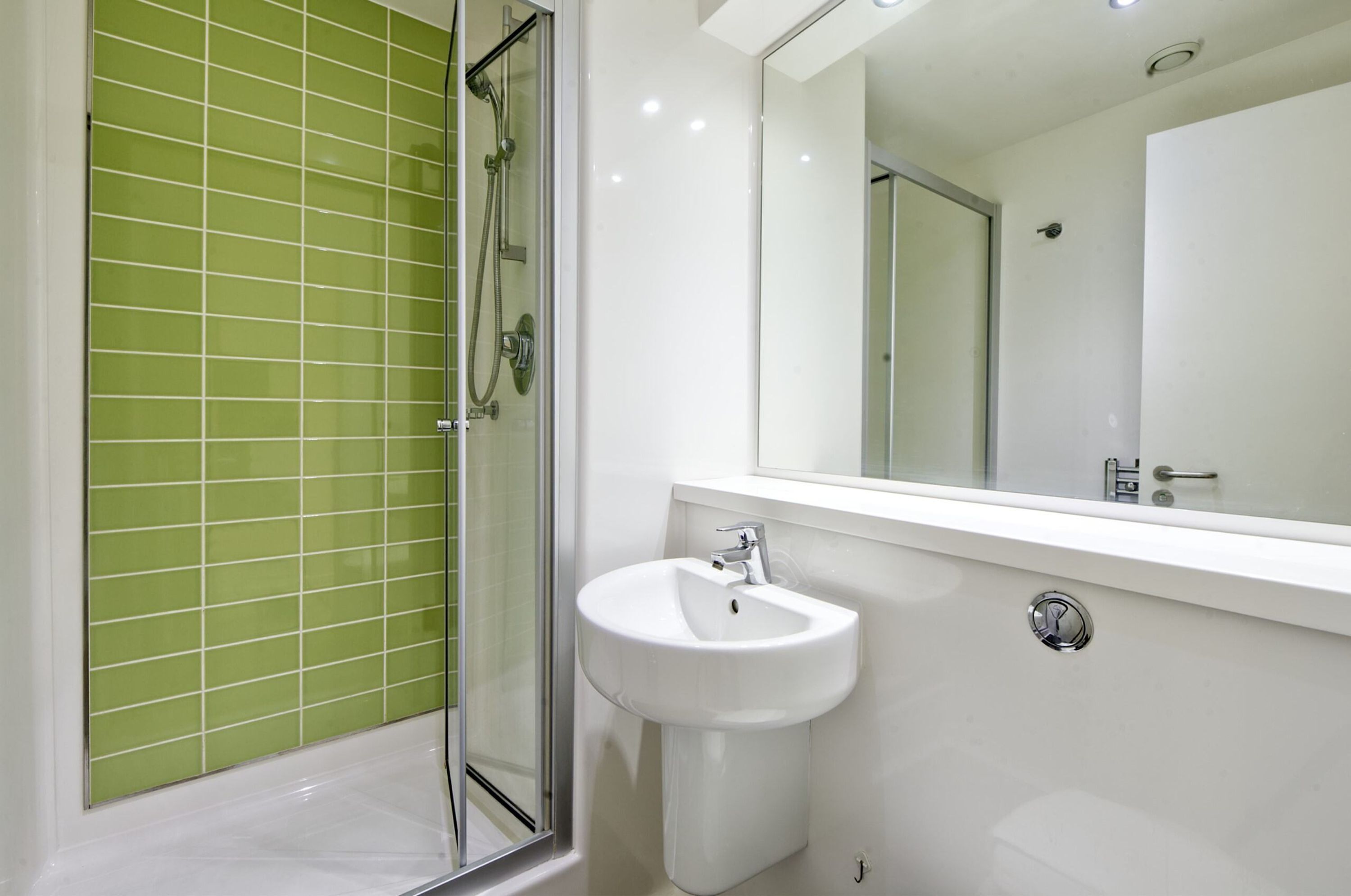 Une salle de bain avec une douche à parois de verre, un lavabo blanc et un miroir au-dessus.