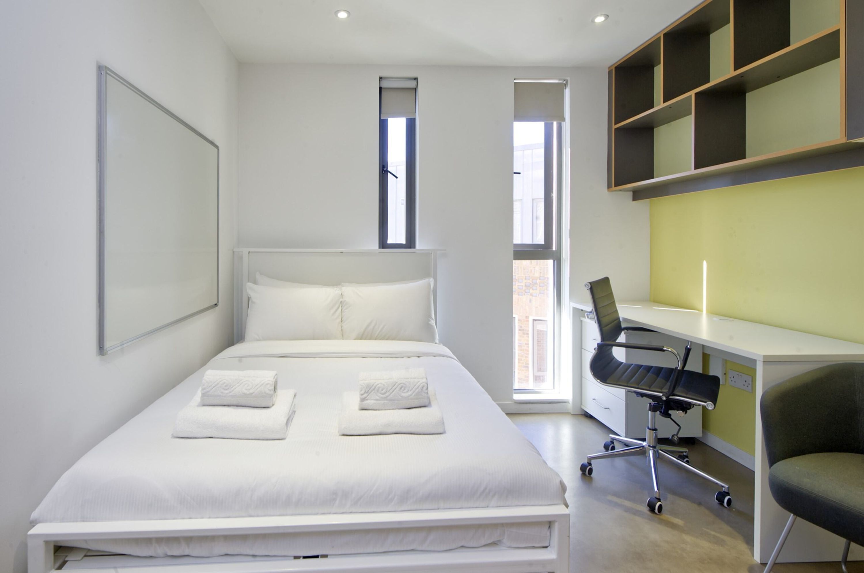 A modern bedroom with a large bed, a desk, and a chair.