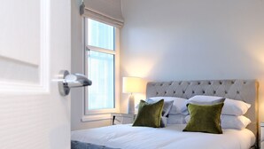 A neatly made bed with a tufted headboard, two pillows, and a bedside lamp. - Modern City Centre Apartment in Aberdeen (Aberdeen)