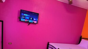 A bedroom with two beds, a ceiling fan, and a mounted TV displaying a home screen. - EL REY MOTEL & RESTAURANT (Belmopan)