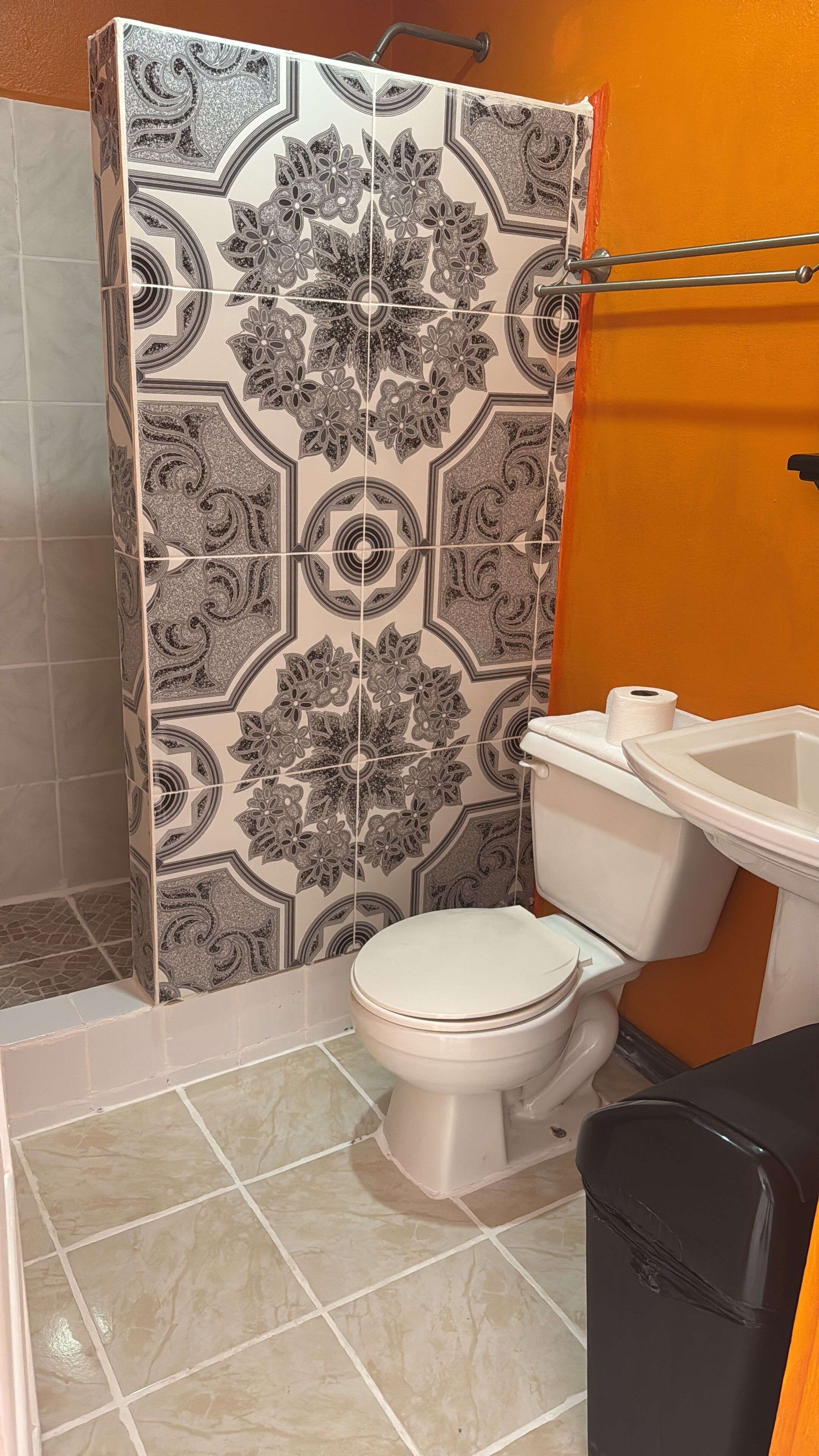 Un baño con cabina de ducha con diseño, inodoro y lavamanos.