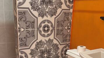 Un baño con cabina de ducha con diseño, inodoro y lavamanos.