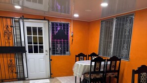 A dining area with a table and chairs, a door, and windows with metal bars. - EL REY MOTEL & RESTAURANT (Belmopan)