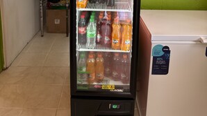 A vending machine stocked with various beverages, including Fanta and Sprite, in a room with green walls and a tiled floor. - EL REY MOTEL & RESTAURANT (Belmopan)