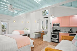 A room with two beds, a kitchenette, and a ceiling fan. - Sea of Dreams 174 SE (Port Aransas)