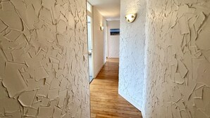 A hallway with textured walls and wooden flooring, leading to a room with a view.