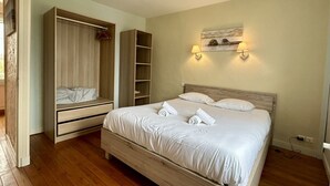 A bedroom with a bed, a wardrobe, a bedside table, and a wall-mounted lamp.