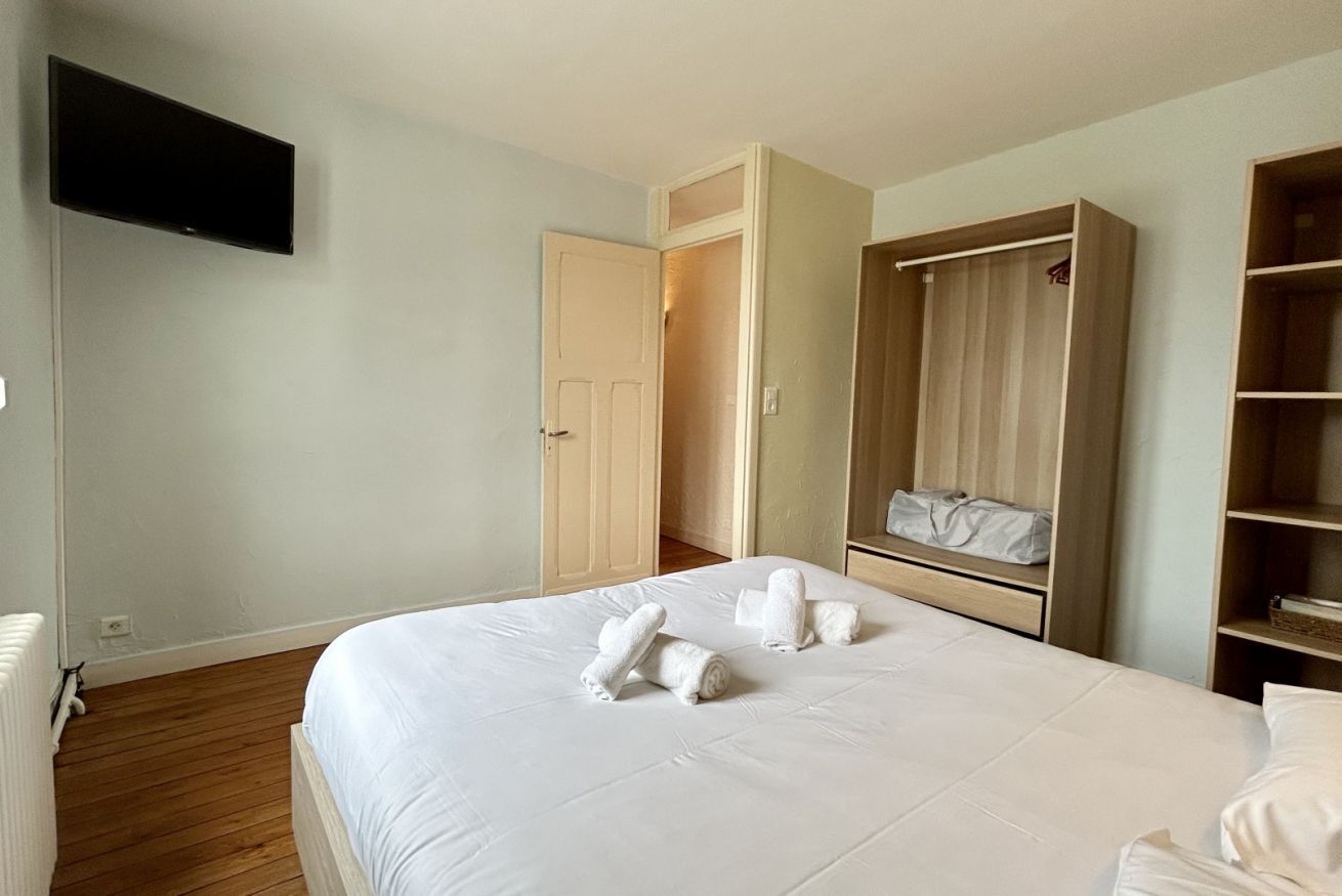 Ein Hotelzimmer mit einem Bett, einem an der Wand befestigten Fernseher, einem Kleiderschrank und einem begehbaren Kleiderschrank.