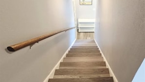 Un escalier en bois, doté d’une rampe et d’une porte blanche en haut.