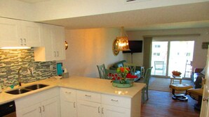 A modern kitchen with white cabinets, a tiled backsplash, and a central island. - Oceanfront End-Unit | Pool View, Washer/Dryer (St. Augustine Beach)