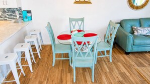 A dining area with a round table, chairs, and a hanging lantern. - Oceanfront End-Unit | Pool View, Washer/Dryer (St. Augustine Beach)