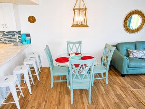 A dining area with a round table, chairs, and a hanging lantern. - Oceanfront End-Unit | Pool View, Washer/Dryer (St. Augustine Beach)