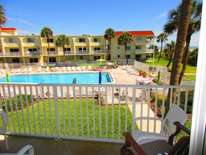 A hotel with a pool area, multiple balconies, and palm trees.
