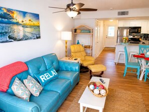 A living room with a blue sofa, a yellow armchair, and a dining area with a table and chairs.