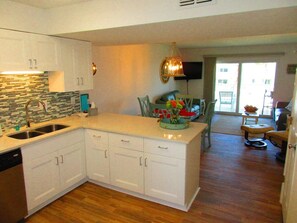 A modern kitchen with white cabinetry, a built-in dishwasher, and a tiled backsplash.