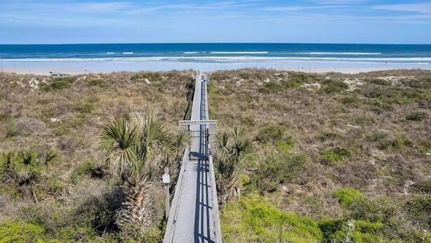 A long, narrow bridge leading to a beach with sparse vegetation and a clear blue sky. - Ocean-View Condo | Pool + Balcony | Crescent Beach (St. Augustine Beach)