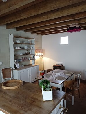 Enjoy a warm and inviting kitchen and dining area with wooden beams, white cabinetry, and a dining table for meals.