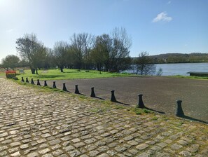 Stroll along the river and enjoy serene views from a bench or picnic table amidst lush trees and a calm river.