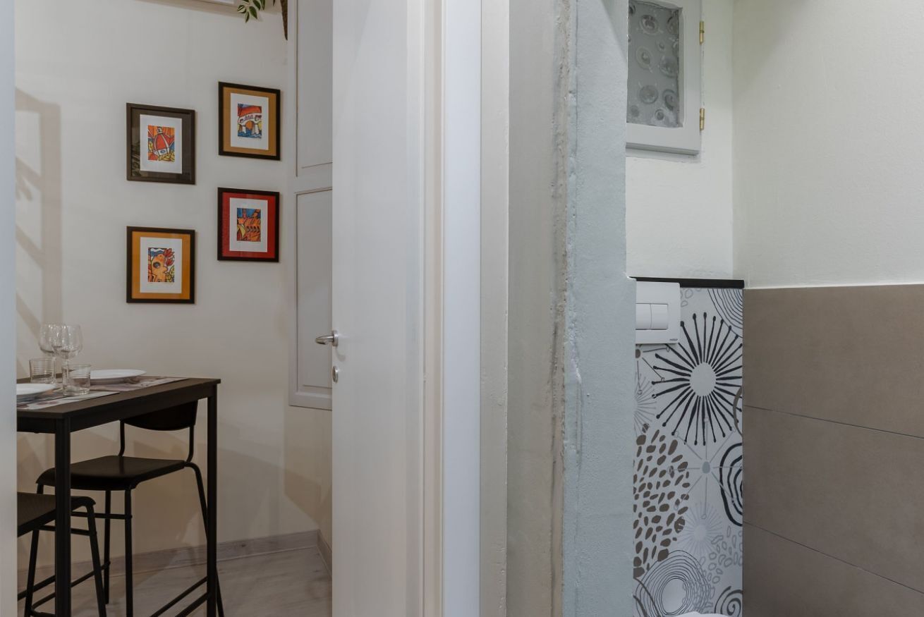 A room with a dining table and chairs, a door, and a wall with framed artwork.