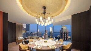 A modern dining room with a round table, multiple chairs, and a city view. - ADEN Hotel Shenzhen Nanshan (Shenzhen)