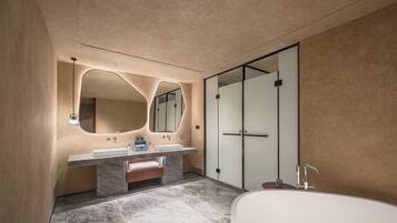 A modern bathroom with a large bathtub, two sinks with marble countertops, and a large mirror with an abstract design.