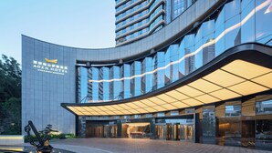 A modern hotel entrance with a curved facade, reflective glass windows, and a prominent entrance with a canopy. - ADEN Hotel Shenzhen Nanshan (Shenzhen)