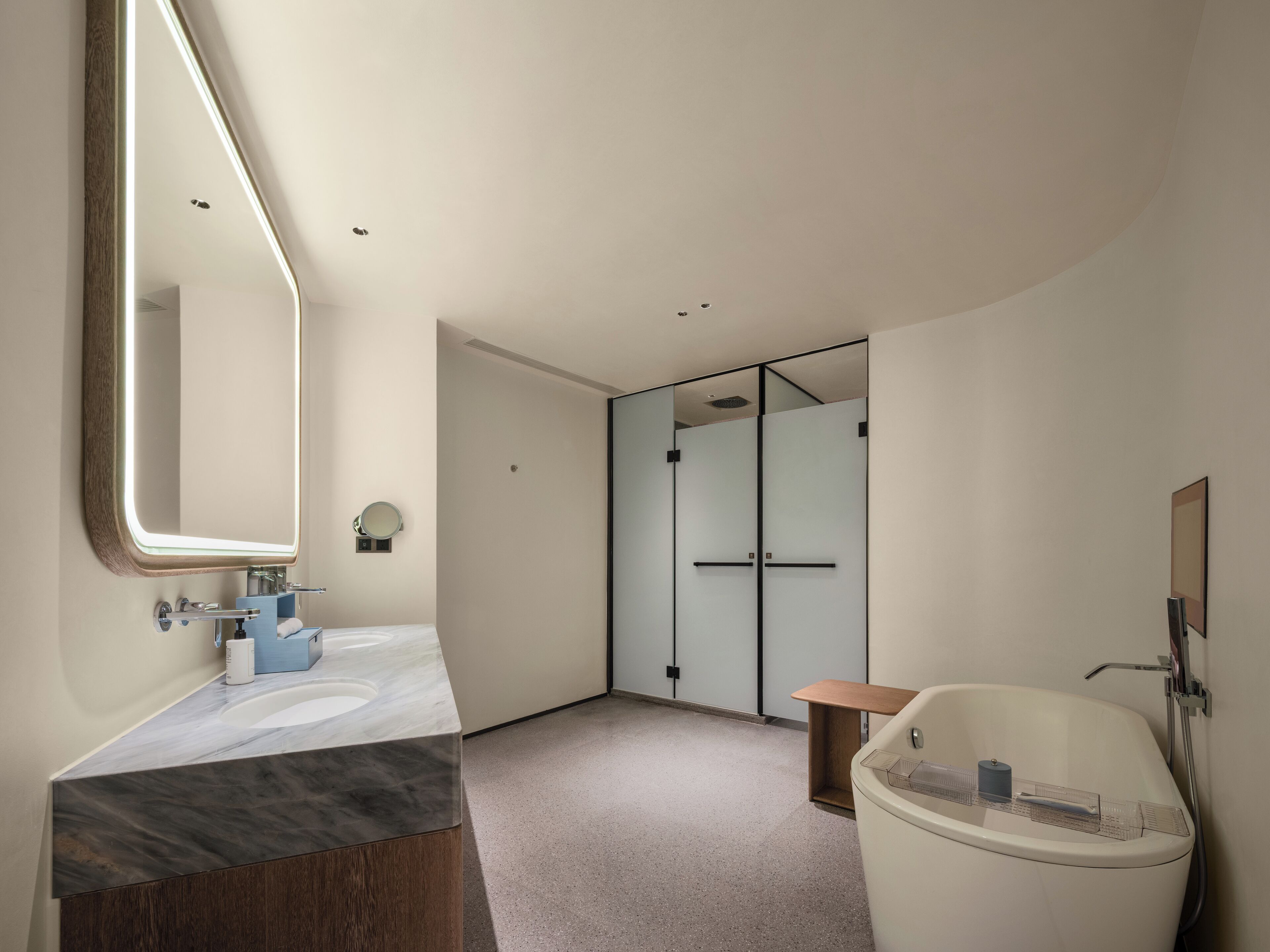 A modern bathroom with a large mirror, a marble vanity, a bathtub, and a glass shower enclosure.