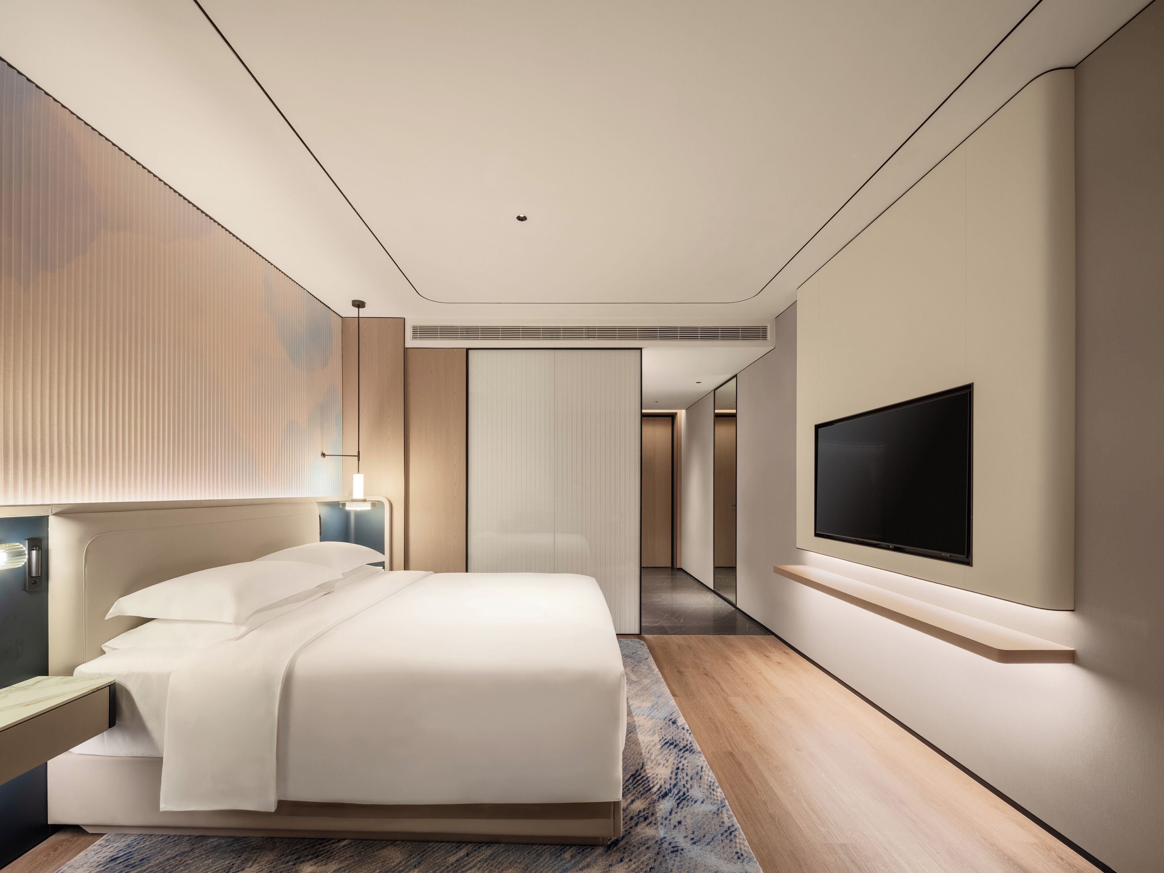 Quarto de hotel moderno com uma cama grande, televisão de tela plana na parede e um closet espaçoso.
