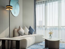 Una sala de estar moderna con un sofá, una mesita auxiliar y una lámpara de pie.
