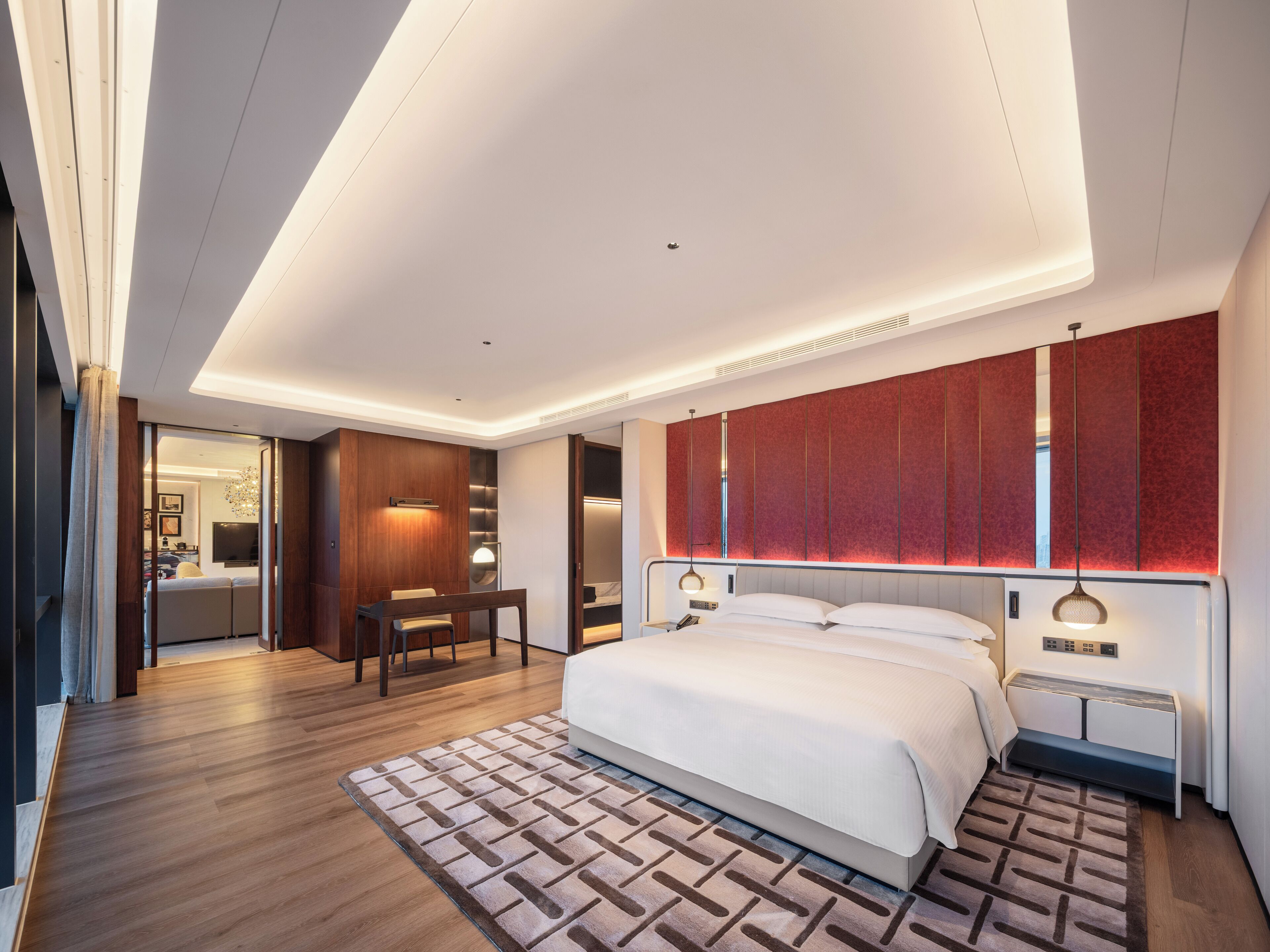 A modern bedroom with a large bed, a desk, and a seating area.