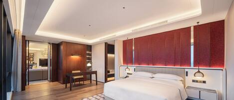 A modern bedroom with a large bed, a desk, and a seating area.