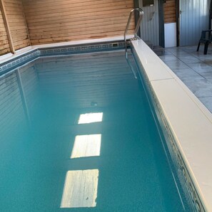 Une piscine dotée d’une terrasse en bois et d’une échelle en métal.