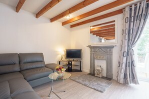 Una sala de estar con sofá, televisión, chimenea y una mesita con fruta.