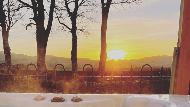 Kylpytynnyri, josta avautuu näkymä puihin ja auringonlaskuun.
