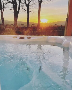 Ein Whirlpool mit Blick auf Bäume und einen Sonnenuntergang.