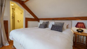 A bedroom with a large bed, wooden beams, and a bedside lamp. - Jane Welsh Cottage - a cottage that sleeps 4 guests  in 2 bedrooms (Thornhill)