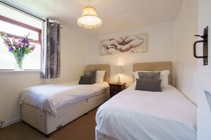Une chambre d’hôtel avec deux lits, une fenêtre avec des rideaux, un luminaire suspendu et une œuvre d’art accrochée au mur.