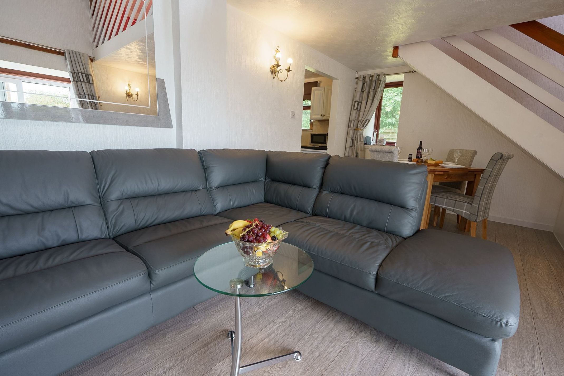 A modern living room with a sectional sofa, a glass coffee table, and a fruit bowl.