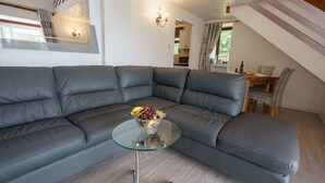 A modern living room with a sectional sofa, a glass coffee table, and a fruit bowl. - Jane Welsh Cottage - a cottage that sleeps 4 guests  in 2 bedrooms (Thornhill)