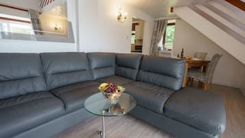 A modern living room with a sectional sofa, a glass coffee table, and a fruit bowl.