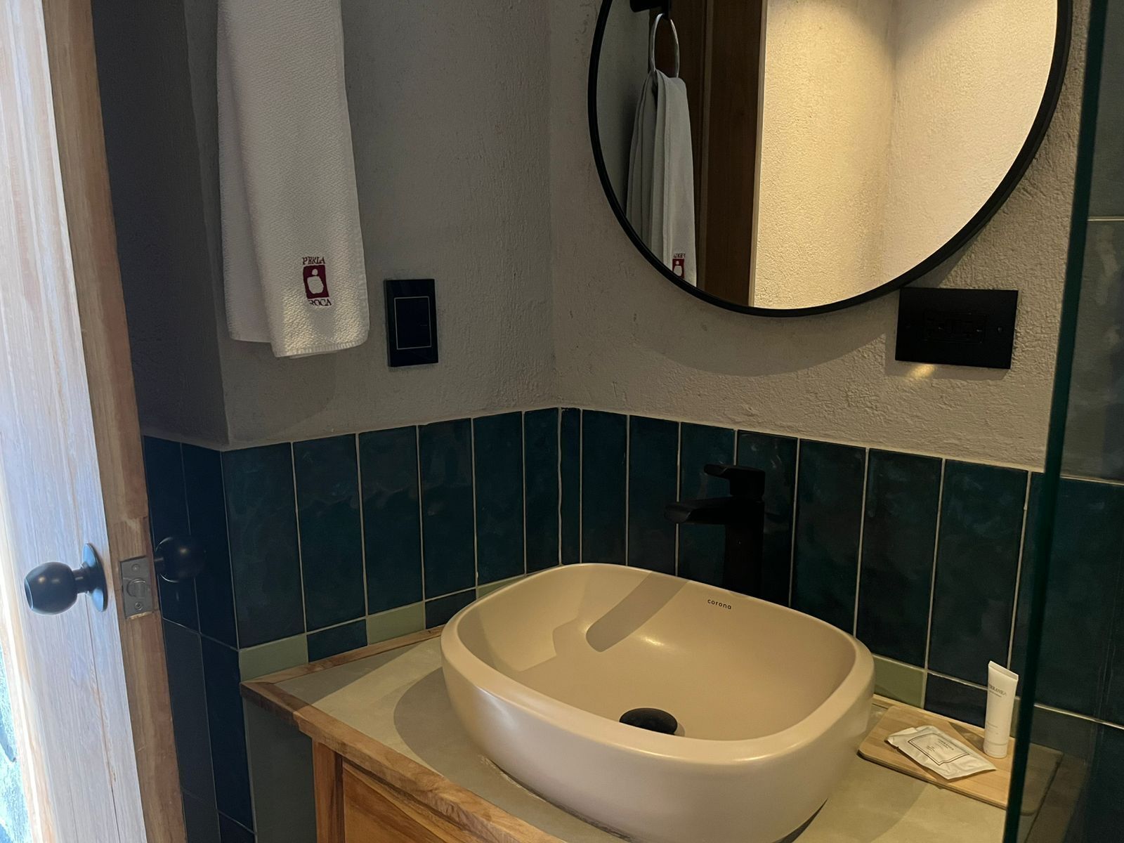 Une salle de bain avec un lavabo blanc, un miroir rond et un porte-serviettes.