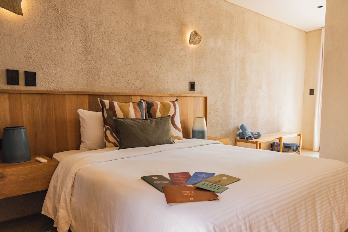 A hotel room with a large bed, wooden headboard, and a textured wall.