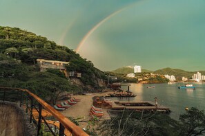 A beach with lounge chairs, a dock, and boats on the water. - Perla Roca Hotel Boutique - Beach Front (Santa Marta)