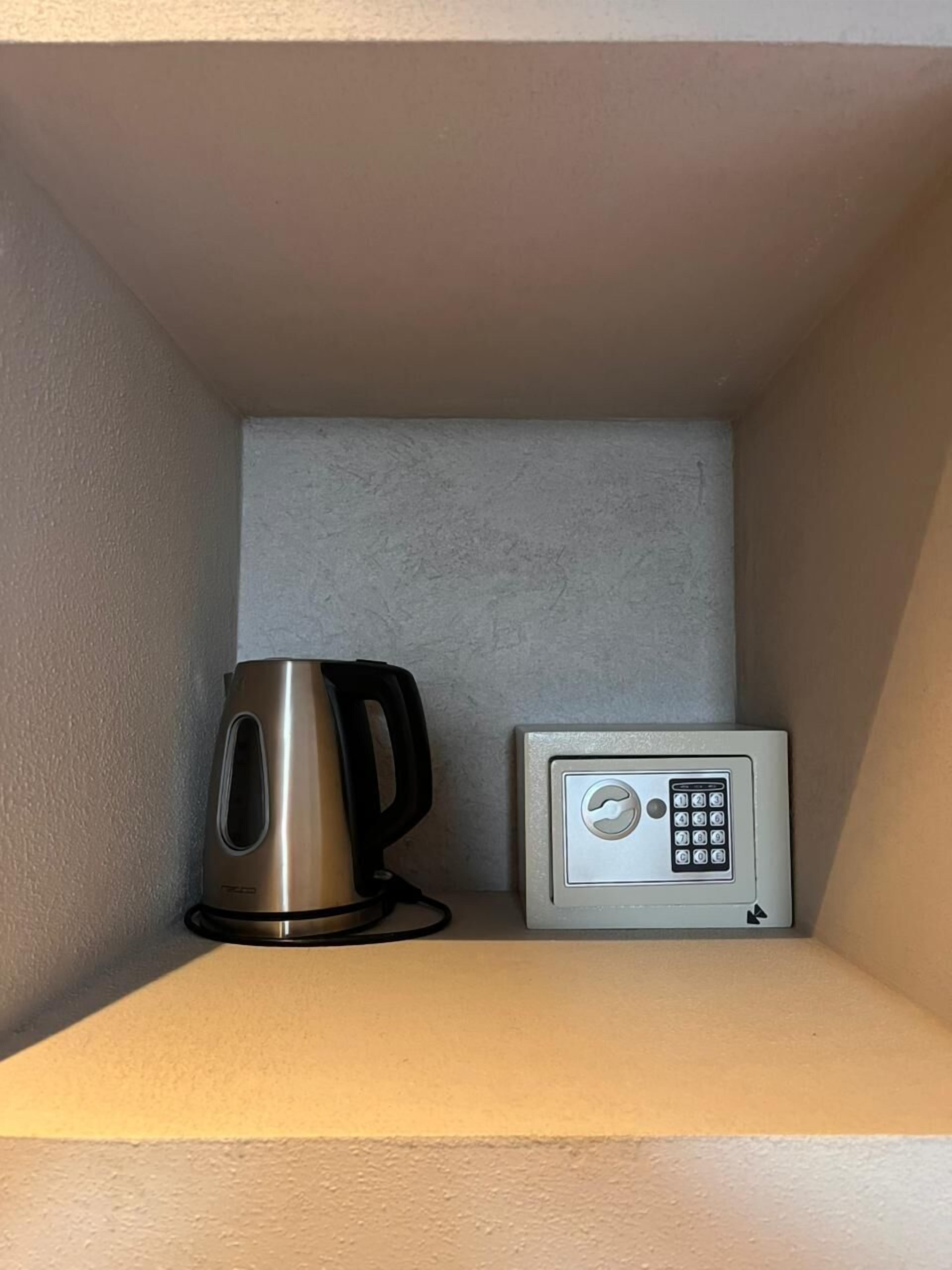 A small storage space with a kettle and a microwave.