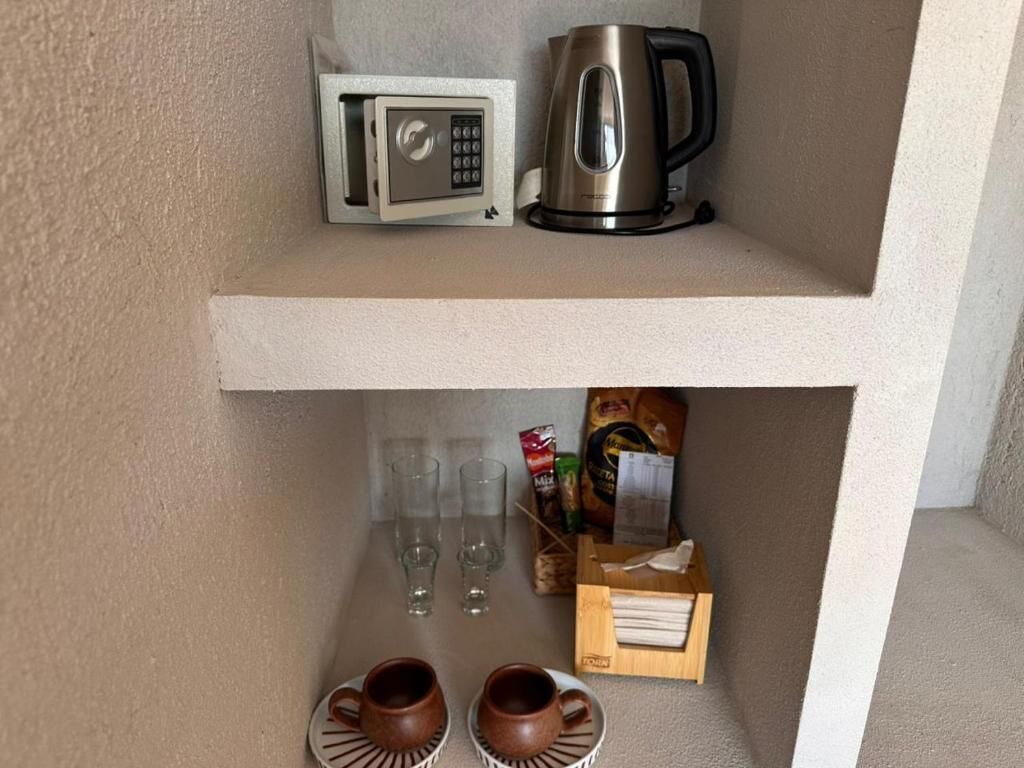 A shelf with a microwave, a coffee maker, and a box of tissues. Below, there are two cups and three glasses.