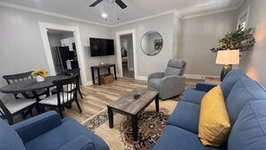 A living room with a sofa, armchair, coffee table, and a TV. - Spacious 3bd/1b home - .9 miles to Casino (Danville)