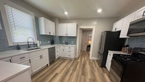A modern kitchen with white cabinets, a black refrigerator, and a wooden floor. - Spacious 3bd/1b home - .9 miles to Casino (Danville)