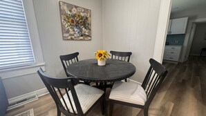 A dining area with a round table, four chairs, a vase with sunflowers, and a painting on the wall. - Spacious 3bd/1b home - .9 miles to Casino (Danville)